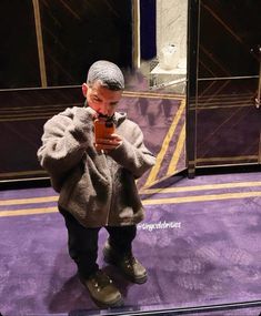 a little boy standing in front of a mirror taking a selfie with his cell phone