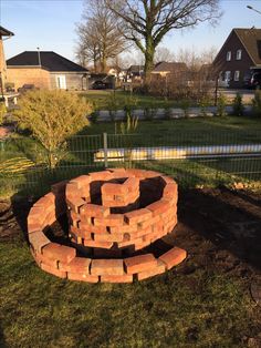 a circular brick fire pit in the middle of a yard