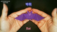 two hands holding a purple origami bat