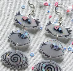 four earrings with different designs on them sitting on a table next to confetti sprinkles