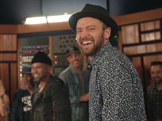 a group of men standing next to each other in front of a recording booth smiling at the camera