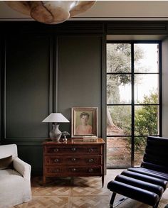 a living room filled with furniture and a painting on top of a wooden dresser next to a window