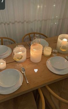 a wooden table topped with white plates and glasses