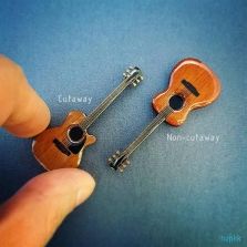 two miniature guitars are being held by a person's hand with the caption