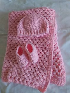 a pink crocheted blanket and hat on a bed