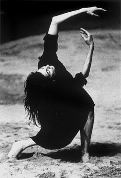 black and white photograph of a woman doing a handstand on the ground with her arms in the air