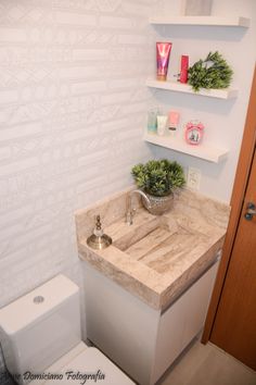 a white toilet sitting next to a sink under a bathroom mirror with shelves above it