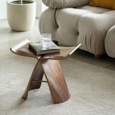 a wooden table sitting on top of a white carpeted floor next to a couch