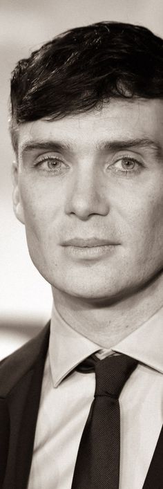 a black and white photo of a young man in a suit with a tie on