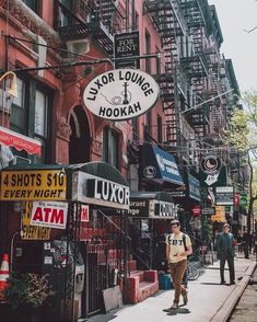 a man walking down the street in front of liquor store signs and stores across from other buildings