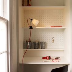 a white desk with a lamp on top of it next to a chair and bookshelf