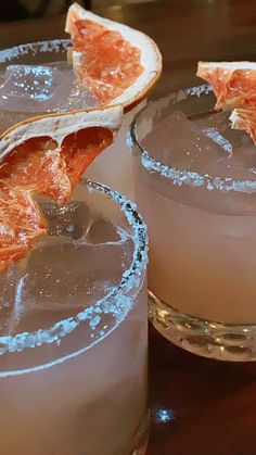 two glasses filled with drinks sitting on top of a table