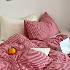 a red and white striped comforter on top of a bed next to an orange
