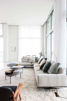 a living room filled with lots of furniture and large windows next to a white rug