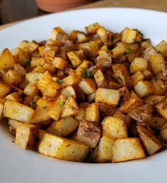 a white plate topped with potatoes on top of a table