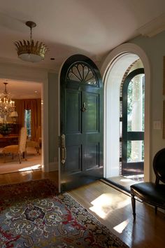 an arched doorway leads to a formal dining room with chandelier and seating area