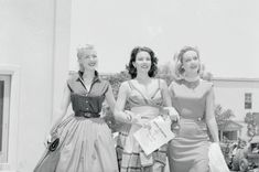 three women standing next to each other in dresses