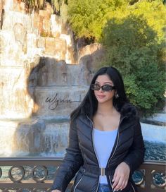 a woman sitting on a bench in front of a waterfall