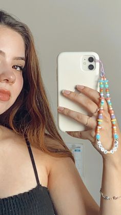 a woman taking a selfie with her cell phone and beaded bracelets around her neck