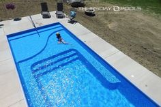 an aerial view of a swimming pool with a person in the water and chairs around it