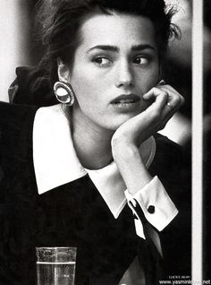 black and white photograph of a woman sitting at a table with a glass in front of her