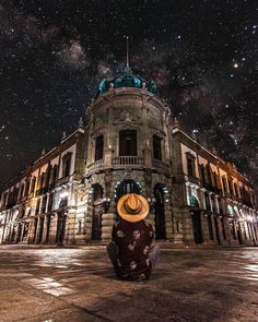 a person wearing a hat sitting on the ground in front of a building with stars