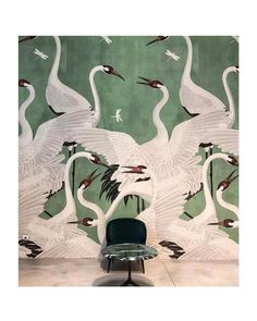 a chair sitting in front of a wall with swans on it and birds flying around