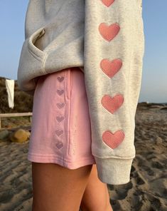 the back of a woman's shorts with hearts drawn on it, while she is walking along the beach