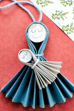 an origami doll holding a fan on top of a red cloth covered table