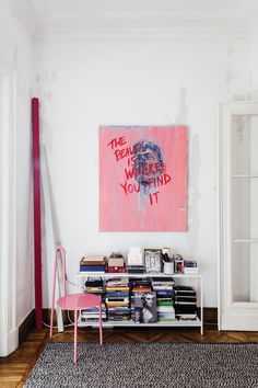 a room with a book shelf and a painting on the wall