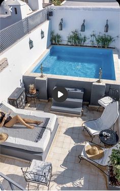 a woman laying on top of a couch next to a swimming pool in a backyard