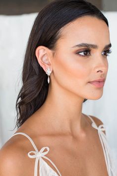 a woman in a white dress with earrings on her head and one ear is shown