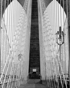 black and white photograph of the brooklyn bridge's pedestrian walkway, looking up at it