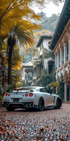 a white sports car parked in front of a large house on a cobblestone street