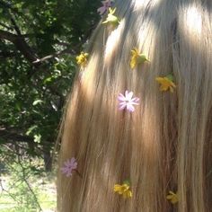 the back of a woman's head with flowers pinned to her long blonde hair