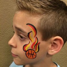 a young boy with his face painted to look like a basketball ball and fireball