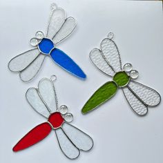 three metal dragonflys sitting on top of a white table next to each other