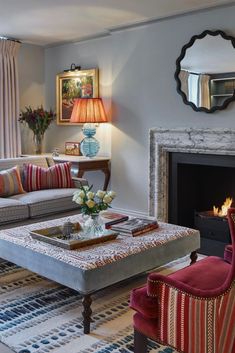 a living room filled with furniture and a fire place in front of a mirror on the wall