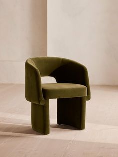 a green chair sitting on top of a hard wood floor next to a white wall