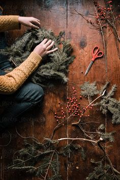 a person is working on some branches with scissors and berries in the foreground, surrounded by twigs