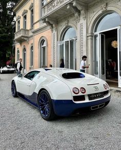 a white and blue bugatti parked in front of a building