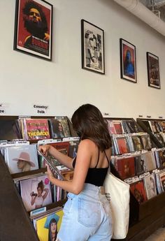 a woman standing in front of a display of vinyl record's at a music store