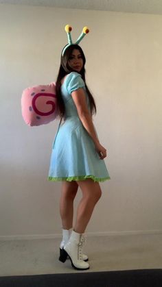 a woman in a blue dress holding a pink ballon with a snail on it's head