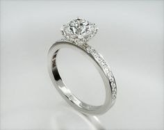 a white gold ring with diamonds on the sides and a center stone in the middle