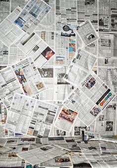 a pile of newspapers sitting on top of a floor covered in newspaper pages and paper clippings