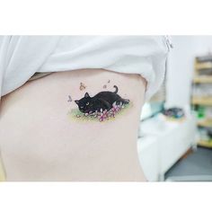 a black cat tattoo on the side of a woman's right ribcage