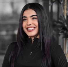 a woman with long black hair smiling at the camera