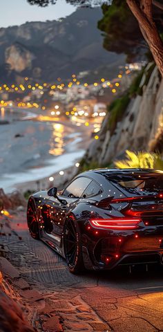 a black sports car parked on the side of a road next to water and trees