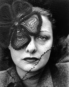 a woman with a butterfly on her face and veil over her eyes, looking at the camera