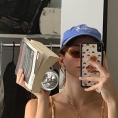 a woman is taking a selfie with her cell phone while holding an open book